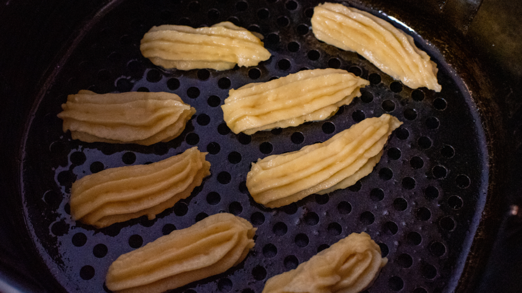 Piped uncooked churros in the air fryer basket