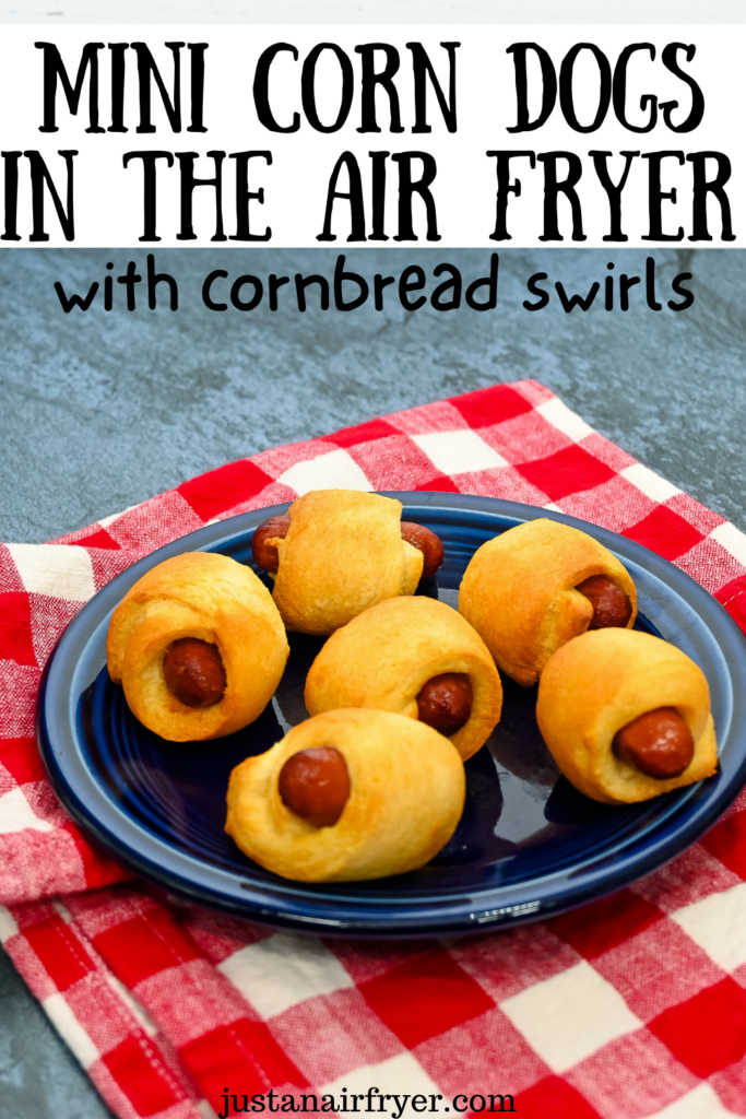 Closeup title image of 6 finished mini corn dogs with cornbread swirls from the air fryer on a dark blue plate on a red plaid napkin