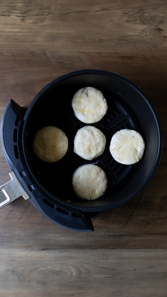 5 air fryer buttermilk biscuits ready to cook in the air fryer basket.