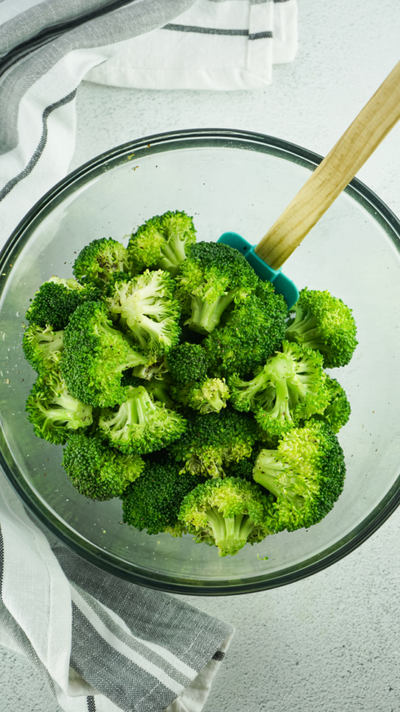 Freshly cooked broccoli from the air fryer getting tossed with additional seasoning.