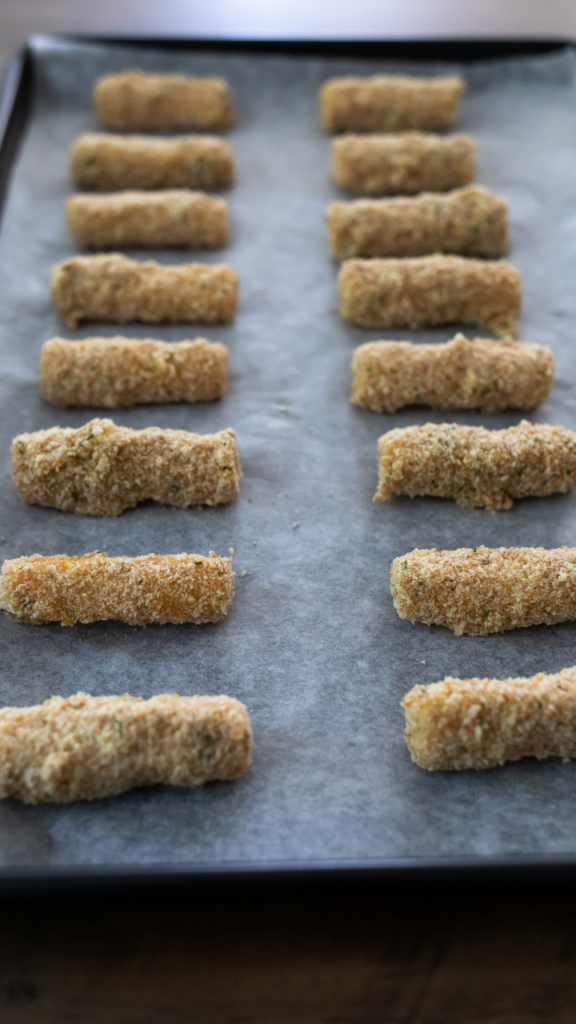 All the dipped mozzarella sticks on a cookie sheet ready to freeze. 