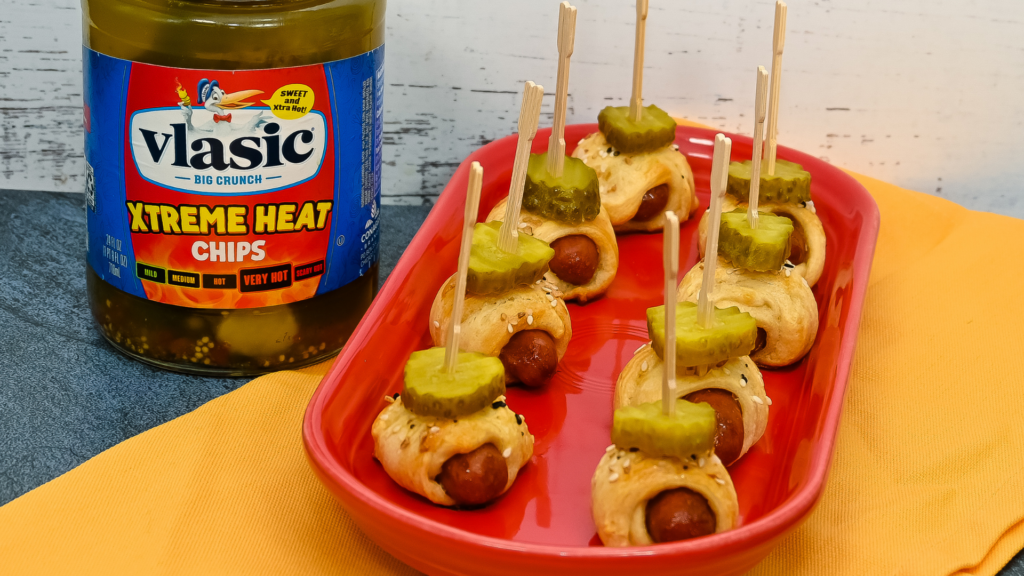 Lil Smokies Pigs in a Blanket in the Air Fryer topped with hot pickles and toothpicks on a red platter. 