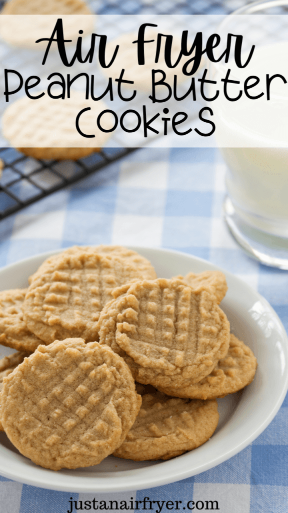 A white plate full of peanut butter cookies on a blue checked towel with a glass of milk. 