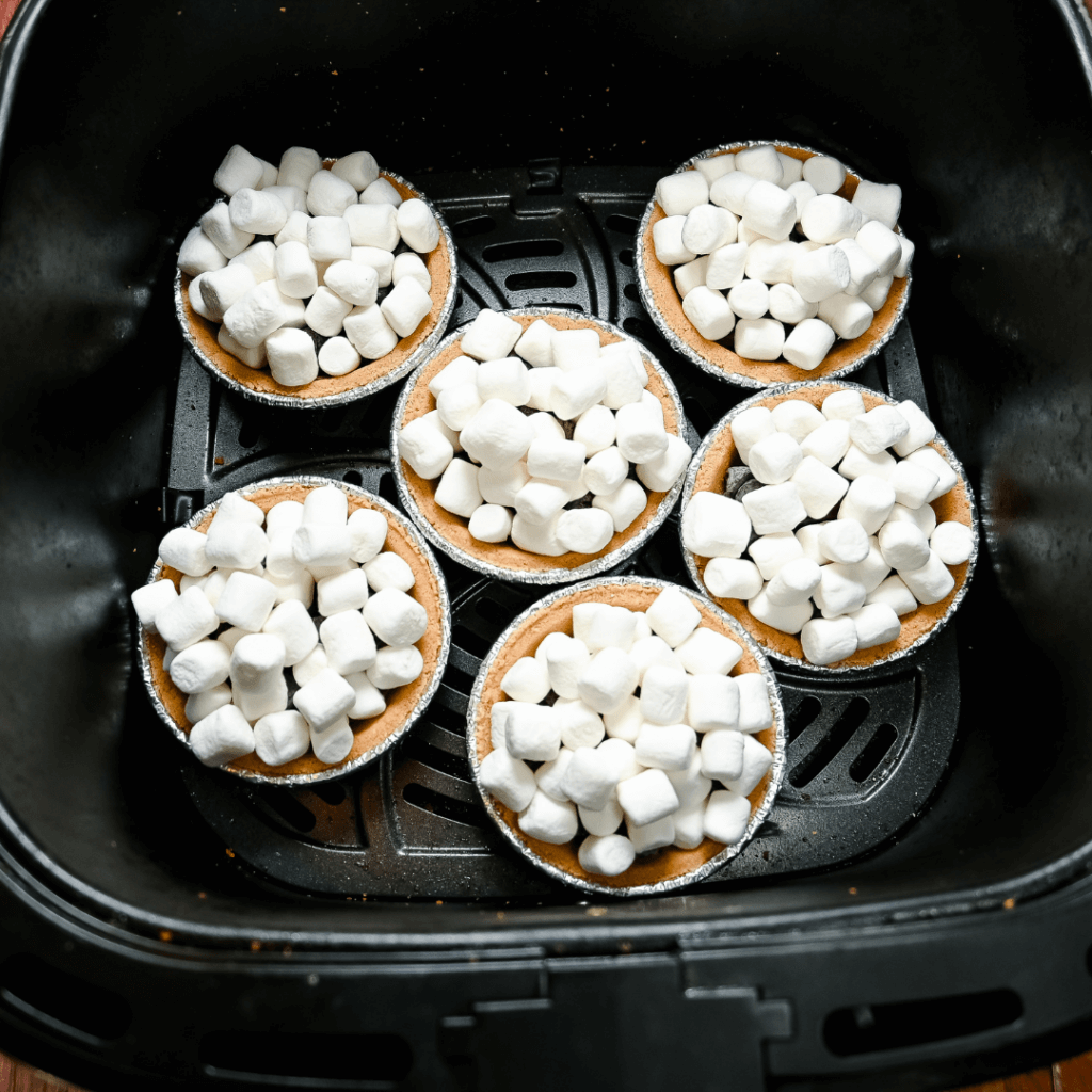 The mini s'mores pies topped with marshmallows in the air fryer basket. 